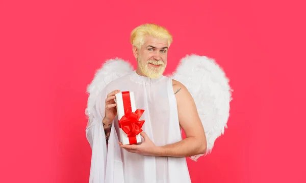 stock image Happy Valentines Day. February 14. Valentines day angel in white wings with Valentine present. Smiling bearded man in angel costume with gift box. Cupid angel with present gift. Valentines day sale