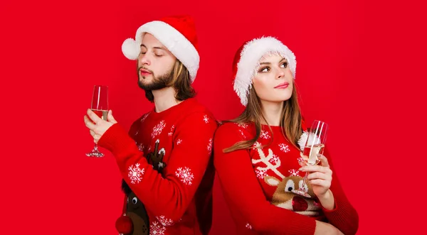 New Year couple with glass champagne. Christmas couple man and woman in Santa hat and Christmas sweater drinks wine. Relationships. New year party. Christmas advertising. Winter holidays celebration