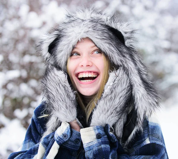 Winter holidays and vacation. Winter fashion for women. Smiling girl in plaid coat, fur hat and mittens. Closeup portrait of Christmas woman in warm clothing in snowy winter park. Cold winter weather
