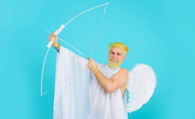 Saint Valentines Day celebration. Smiling bearded man in angel wings with bow and arrow. God of love. Valentines day Cupid shooting arrows of love with bow. February 14. Male angel with bow and arrow