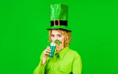 Saint Patricks day celebration. Blonde woman in leprechaun hat with glass of green beer. Patrick day pub party. Beautiful girl in green top hat and jacket drinking beer. Glass of beer with shamrock