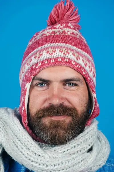 Men winter fashion. Closeup portrait of smiling man in knitted scarf and hat. Fashion accessories for winter. Handsome trendy man in winter hat and scarf. Fashionable bearded male in winter clothes