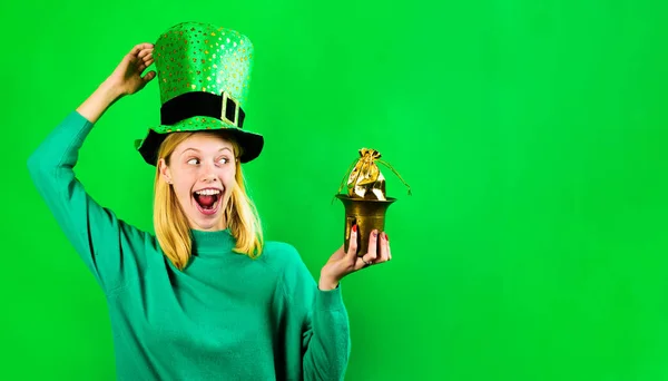 Patricks Day. Irish tradition. Pot with money for Patricks day party. Happy blonde woman in Leprechaun top hat with pot of gold. Smiling girl in Leprechaun green costume with pot of gold. Copy space