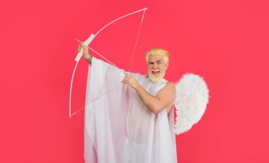 Sevgililer günün kutlu olsun. Melek kostümü giymiş, yaylı gülümseyen sakallı adam. Sevgililer günü meleği aşkın okunu atıyor. Sevgililer günü meleğin kanatlarında ok ve yayla aşk tanrısı. Sevgililer günü alışverişi