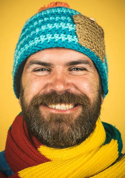 Portrait of handsome man in knitted hat and scarf. Casual look. Smiling bearded man in colorful scarf and woolen hat. Fashionable man in winter clothes. Men autumn-winter fashion. Winter accessories