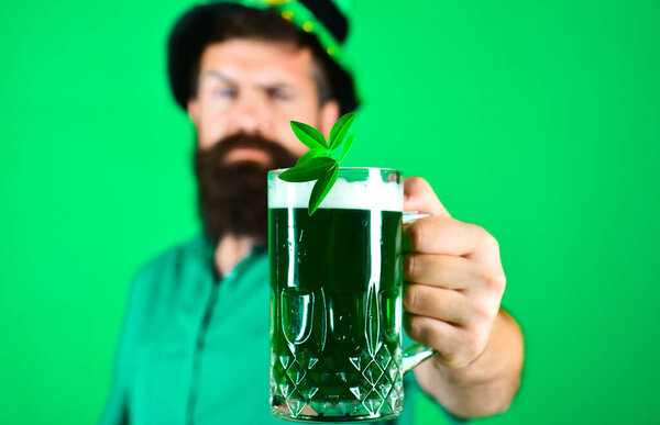 Patricks day pub party celebration. Selective focus on mug green beer with clover in hand of bearded man. Ireland tradition. Traditional Irish festival. March 17. Patricks day advertising. Closeup