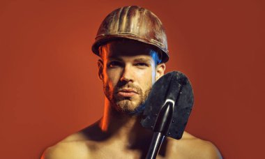 Koruyucu miğferi ve küreği olan ciddi bir profesyonel müteahhit. Kendine güvenen mimar, kürekle kasklı tamirci. Ağır sanayi ve madencilik. Güvenlik kaskı takmış zalim inşaat işçisi ya da madenci