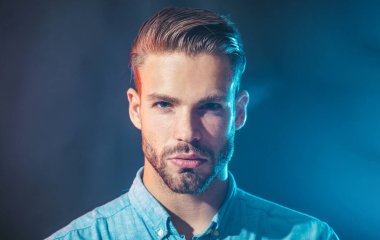 Erkek portresi. Kot gömlekli ciddi modaya uygun sakallı bir adam. Sakallı ve bıyıklı seksi, yakışıklı bir erkek model. Şık saç stili olan çekici, tıraşsız bir adam. Erkekler için gündelik moda