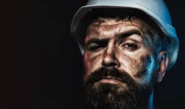 Closeup portrait of construction worker in hard hat. Pensive bearded man in protective helmet. Serious professional architect, contractor or male builder in safety hardhat. Copy space for advertising