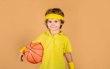 Çocuklar için spor. Futbol formalı küçük bir basketbolcu. Hobi spor konsepti. Fitness, eğitim ve sağlıklı yaşam tarzı. Basketbol topuyla spor giyimli yakışıklı bir çocuk. Spor oyunu