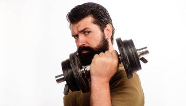 Elinde dambıl olan ciddi bir adam. Spor kulübünde sakallı sporcu dambılı kaldırıyor. Spor salonunda vücut geliştirmede güçlü yakışıklı bir vücut geliştirici. Ağırlık çalışması. Kas geliştirme modeli dambılı kaldırıyor