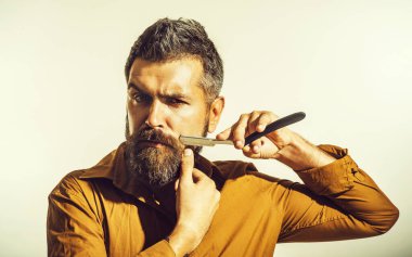 Berber dükkanı reklamı. Sakallı, bıyıklı ve usturalı yakışıklı bir erkek. Düz usturalı şık gömlekli sakallı adam. Profesyonel sakal bakımı. Berber aksesuarları. Klasik berber dükkanı.