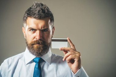 Beyaz gömlekli ve mavi kravatlı yakışıklı sakallı adam manyetik çizgili kredi kartı gösteriyor. Reklam bankacılığı hizmetleri, kredi veya mevduat için kopyalama alanı. Kredi kartıyla resmi kıyafet giyen bir iş adamı.