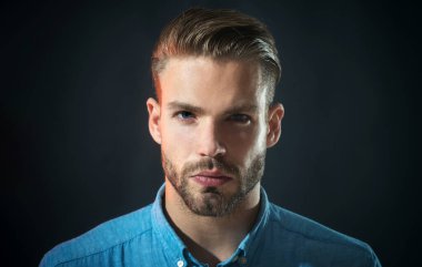 Kot gömlekli sakallı adamın yakın plan portresi. Sıradan giyinmiş ciddi bir iş adamı. Sakallı ve bıyıklı yakışıklı, tıraşsız adam. Şık saç stili olan seksi erkek model. Erkekler için moda.