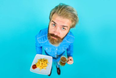 Fast food. Lezzetli patates kızartması ve ketçaplı bira bardağıyla sakallı adam. Lezzetli yemek. Barda bira içip patates kızartması yiyen çekici bir adam. Abur cubur. Sağlıksız beslenme