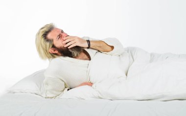 Sabahları rahat bir yatakta uyanıp esneyen bornozlu yakışıklı bir adam. Uykulu adam yatak odasında palmiyeyle ağzını kapatıyor. Sakallı adam yumuşak beyaz yastığın üzerinde uzanıyor. Esne ve uyu.