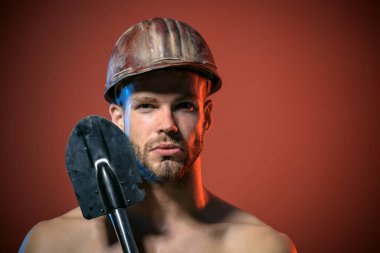 Profesyonel müteahhit ya da koruyucu miğferli maşrapanın yakın plan portresi. Ciddi bir mimar, güvenlik kasketi takmış, istihkamcı küreğiyle tamirci. Ağır sanayi, inşaat ve madencilik kavramı