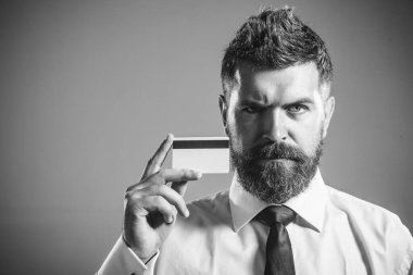 Kredi kartı ya da banka kartı olan bir iş adamı. Ciddi sakallı adam kredi kartı gösteriyor. Banka servisi, kredi ya da mevduat. Alışveriş, e-para, online bankacılık, nakit ödeme, internet bankası. Siyah ve beyaz