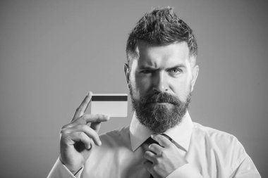 Kredi kartı ya da banka kartı olan kendine güvenen bir iş adamı. Ciddi sakallı adam kredi kartı gösteriyor. Banka servisi, kredi ya da mevduat. İnternetten alışveriş, e-para, nakit ödeme, internet bankası. Siyah ve beyaz