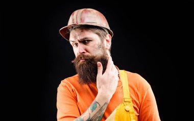 İnşaatçı adam. Erkek müteahhit, koruyucu şapkalı ve tulumlu inşaat mühendisi. Ciddi bir sanayi işçisi, ustabaşı ya da güvenlik şapkalı bir tamirci. İnşaat miğferindeki mekanik işçinin portresi