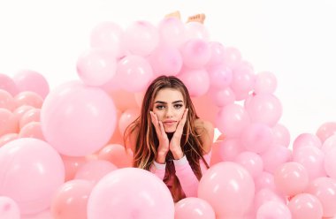 Hava balonlu tatil süsü. Pembe balonların içinde yatan uzun saçlı seksi kız. Parti için hazırlık. Doğum gününü ya da yıldönümünü kutlayan güzel makyajlı genç bir kadın.