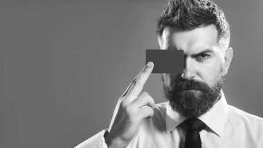 Kredi kartı ya da banka kartıyla gözü kapatan yakışıklı bir iş adamı. Satış, finans, alışveriş ve para. Banka kartı ya da kredi kartı olan ciddi sakallı bir adam. Siyah ve beyaz. Reklam için boşluk kopyala