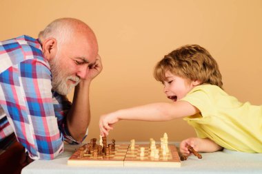 Büyükbabam ve torunum birlikte satranç oynuyorlar. Büyükbabam toruna satranç oynamayı öğretiyor. Satranç yarışması. Hobi ve boş zaman aktivitesi. Çocuk, büyükbabasıyla boş zaman geçiriyor. Mantık oyunları