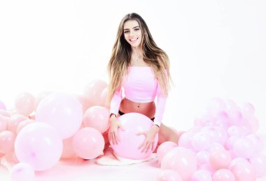 Pembe balonlarla poz veren gülümseyen genç kız. Doğum günü, yıldönümü ve kutlama konsepti. Doğum günü partisinde uzun saçlı ve neşeli makyajlı güzel bir kadın manken. Balonlu tatil süslemesi