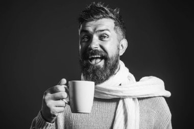 Süveter ve eşarplı mutlu sakallı adam bir fincan kahve ya da çay ile. Sakallı ve bıyıklı yakışıklı bir adam kafede kahve ya da kapuçino içiyor. Sıcak içecekle gülümseyen adam. Siyah ve beyaz