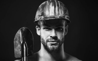 Kürekli sağlam şapkalı ciddi bir müteahhit. İnşaat işçisi, sanayici, tamirci ya da maşalı koruyucu kasklı madenci. Sakallı mekanik ya da endüstriyel işçi istihkam küreği. Siyah ve beyaz