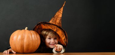 Cadılar Bayramı şapkalı Cadılar Bayramı çocuğu ve balkabağı seni işaret ediyor. Cadılar Bayramı kostümü içinde balkabaklı şirin bir çocuk. Cadılar Bayramı indirimi, alışveriş ve indirim. Reklam için alanı kopyala