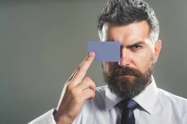 Elinde boş kartviziti olan yakışıklı bir adam. Kredi kartı ya da banka kartı olan resmi giyimli bir iş adamı. Ciddi sakallı adam banka kartını gösteriyor. Ödeme işlemi, e-para ve finansal konsept. Boşluğu kopyala
