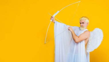 Sevgililer Günü. Ok ve yaylı erkek melek. Melek kanatlı sakallı adam aşk oku atıyor. Sevgililer Günü 'nde ok ve yayla melek kostümü giymiş yakışıklı bir adam. İndirim ve indirim. Boşluğu kopyala