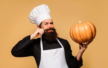 Male chef with pumpkin. Satisfied bearded cook in chef hat and uniform with pumpkin. Organic food. Healthy product. Useful vegetables. Bearded chef, cook or baker with big pumpkin for restaurant menu clipart