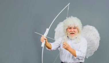 Sevgililer Günü kutlaması. Melek kanatlı mutlu sakallı adam ve yaydan aşk oku atan kıvırcık peruk. Aşk Tanrısı. Ok ve yaylı sevgililer günü meleği. Reklam için boşluk kopyala