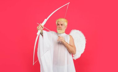 Aşk Tanrısı. Sevgililer Günü kutlaması. Melek kostümü giymiş dalgın sakallı adam ve ok ve yaylı beyaz kanatlar. Sevgililer günü aşığı melek kanatlarıyla yaydan aşk oku atıyor. Aşkın sembolü