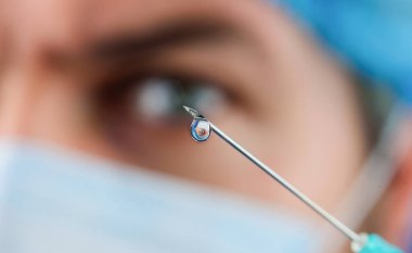 Sıvı ilaç ya da şırınga iğnesindeki uyuşturucu damlası. Aşılama. İğne için şırıngalı bir doktor. Tıbbi enjeksiyon iğnesinin ucuyla bir damla ilaç. Seçici odak