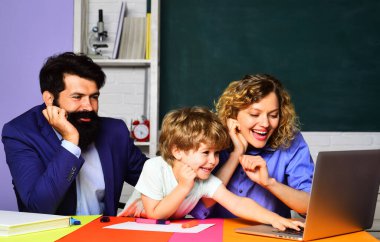 Özel ders. Öğretmenler ilkokuldaki çocuğa dizüstü bilgisayar kullanmayı öğretiyor. Erkek ve bayan öğretmenler sınıfta dizüstü bilgisayar kullanarak çocukların ev ödevlerine yardım ederler. Modern eğitim teknolojisi ve e-öğrenim