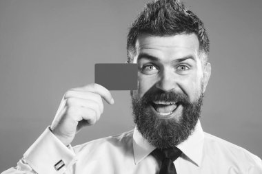 Gülümseyen sakallı iş adamı, bankacı ya da banka müşterisi kredi kartı gösteriyor. E-ticaret, nakit ödeme, nakit para, kredi, e-bankacılık, para, finans. Bankacılık reklamı. Siyah ve beyaz