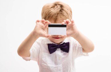 Kredi kartı olan küçük bir çocuk. Gülümseyen çocuğun boş banka hesabı ya da manyetik çizgili ödeme kartı gösteren yakın plan portresi. Plastik banka kartı olan beyaz tişörtlü yakışıklı bir çocuk. Bankacılık reklamı