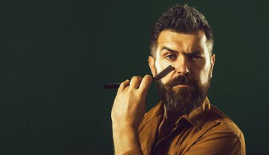 Berber. Erkekler için bir salon. Tıraş olmak için tıraş bıçağı olan sakallı bir adam. Berber dükkanında klasik tıraş. Sakallı yakışıklı adam usturayı düz tutuyor. Berber dükkanı servisi. Berber dükkanı reklamları için yer kopyala