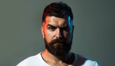Erkek portresi. Sakallı ve bıyıklı, rahat giyimli, kendine güveni tam bir adam. Acımasız sakallı adamın yakın plan portresi. Güzel saç stili olan yakışıklı sakallı adam. Beyaz tişörtlü modacı erkek.
