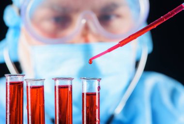 Kan testi. Doktor laboratuvarda hastanın kan örneğiyle çalışıyor. Pipette kan damlası, seçici odaklanma. Tıbbi bilimci ya da laboratuvar asistanı test tüplerindeki kan örneklerini inceliyor. Serolojik test