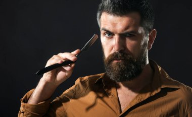 Berber dükkanı servisi. Tıraş adamım. Düz usturalı sakallı adam. Sakal bakımı. Sakallı ve bıyıklı yakışıklı erkek tıraş olmak için klasik tıraş bıçağı tutuyor. Berber dükkanında klasik tıraş. Berber malzemeleri.