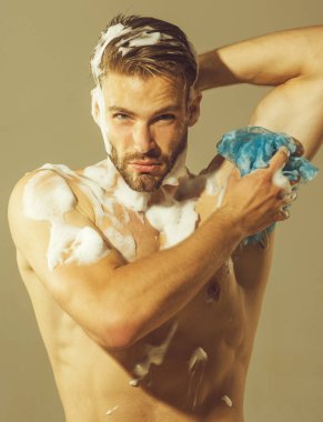 Seksi atletik kaslı adam duş alıyor ve sabunlu süngerle yıkıyor. Spa, hijyen ve rahatlama. Gövdesi kaslı yakışıklı bir adam vücudunu duş jeliyle yıkıyor. Erkekler makyaj malzemesi yağmuru