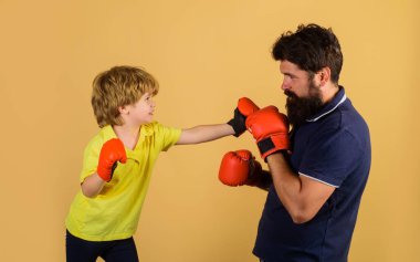 Çocuk boksör boks antrenmanında koçla yumruk antrenmanı yapıyor. Küçük oğlum babasıyla spor salonunda boks egzersizleri yapıyor. Çocuk ve koç boks ringinde. Boks eldivenli çocuk ve antrenör. Geleceğin şampiyonu..