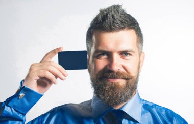 Şık gömlekli, sırıtan sakallı adam kredi kartı, banka hesabı ya da ödeme kartı şablonu gösteriyor. Nakitsiz ödeme. Kredi kartı güvenli online ödeme olarak. Yakışıklı iş adamı boş bir model kartvizit sunuyor.