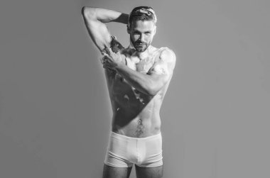 Boxer şortlu kaslı seksi adam banyoda duş alıyor. Temizleyici köpük ve süngerle vücudu yıkayan yakışıklı bir adam. Siyah ve beyaz. Çekici adam nemlendirici jelle duş alıyor. Vücut bakımı