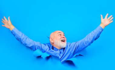 Mutlu yaşlı sakallı adam kağıttaki delikten bakıyor. Şık gömlekli gülümseyen son sınıf öğrencisi el kaldırdı. Yırtılmış kağıt deliğinden bakan yakışıklı bir erkek. Sezonluk satışlar, indirim. Reklam için boşluk kopyala