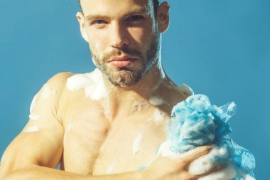 Kaslı seksi adam banyoda duş alıyor. Yakından çekilen portre yakışıklı genç adam cesedi temizleyici köpük ve süngerle yıkıyor. Vücut bakımı ve cilt bakımı. Çekici adam nemlendirici jelle duş alıyor.